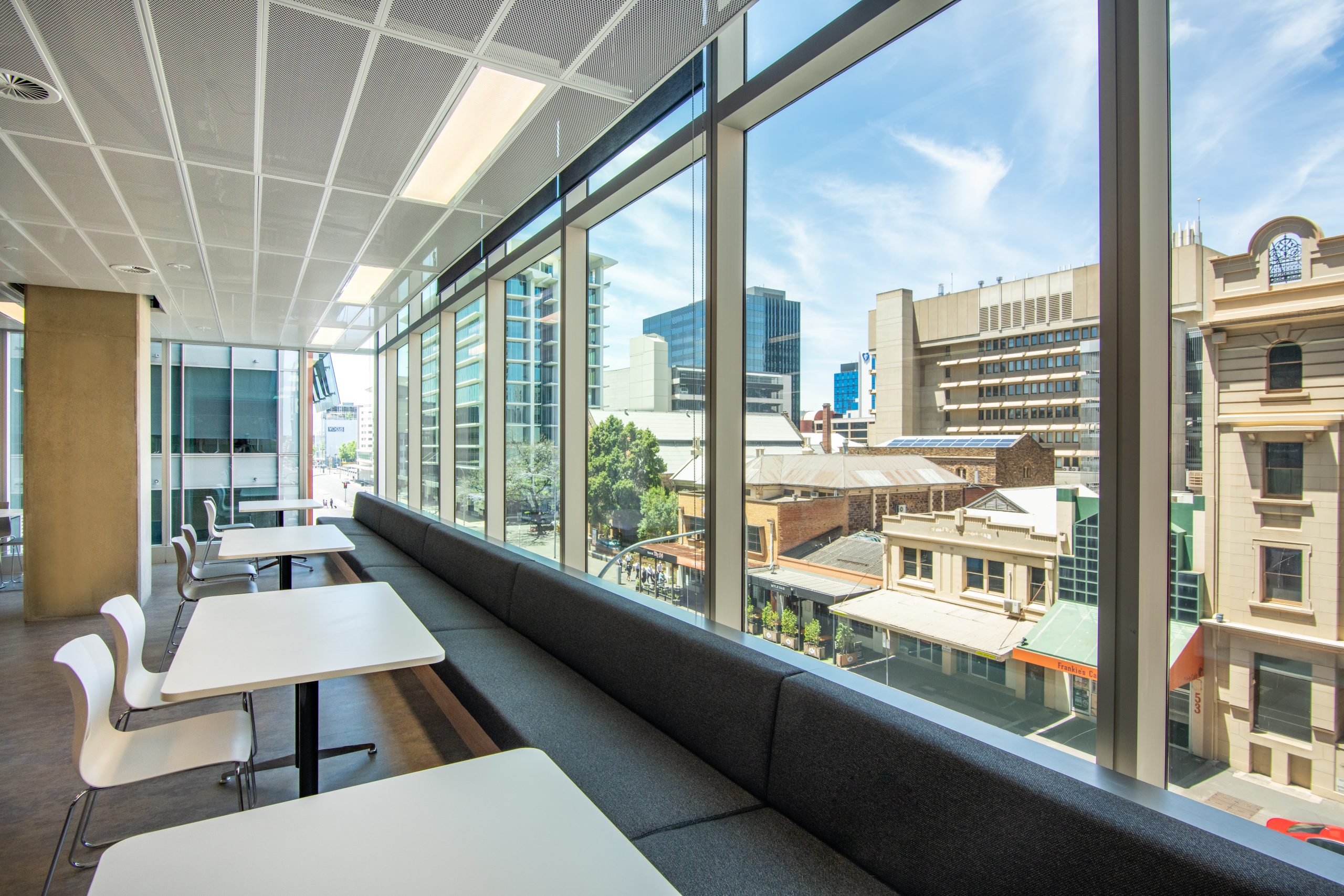 NDIA Office dining area, bench and chair seating with window looking out over Adelaide city.